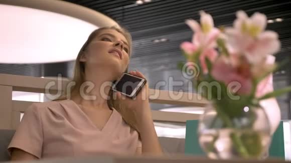 年轻漂亮的女孩坐在rastaurant在智能手机上聊天放松概念交流概念视频的预览图