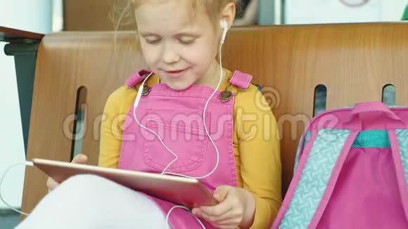 学龄前女孩在户外使用耳机和电脑平板电脑光天化日视频的预览图
