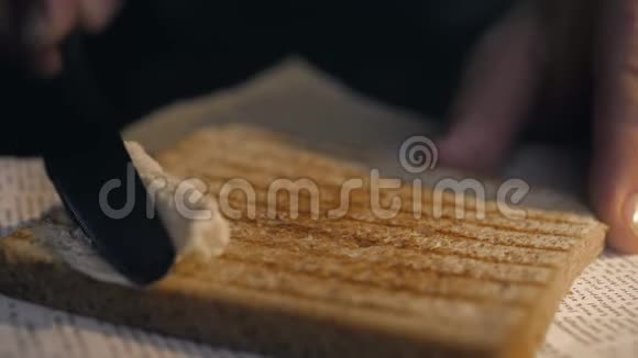 特写镜头厨师用刀把黄油涂在脆烤面包上做三明治自制快餐视频的预览图
