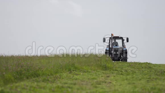 蓝拖拉机在灰色的天空下农场的草地上视频的预览图