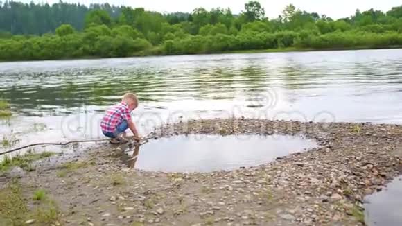 一个孩子在河岸上玩耍美丽的夏天景观户外娱乐活动视频的预览图