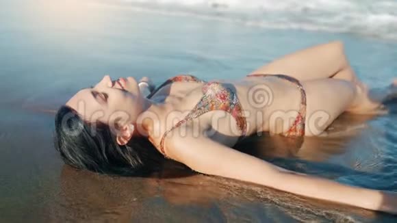 穿比基尼的年轻女孩躺在海边和日光浴视频的预览图