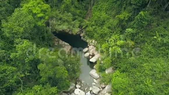 在森林中绿色的树木和植物中流淌着热带河流和岩石瀑布无人机可以看到岩石河和热带视频的预览图