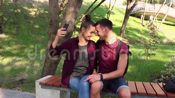 恋爱中的年轻夫妇被拍到坐在公园的长凳上他们微笑着拥抱着对方视频的预览图