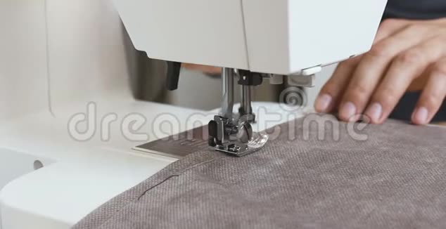 男裁缝工手拿布在缝纫机后面视频的预览图