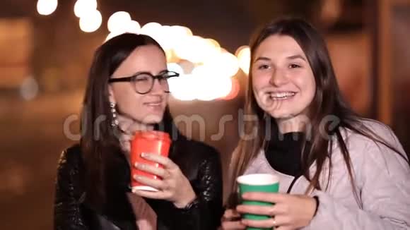 一个秋天的傍晚两个年轻的女孩走在陌生城市的街道上喝着咖啡视频的预览图