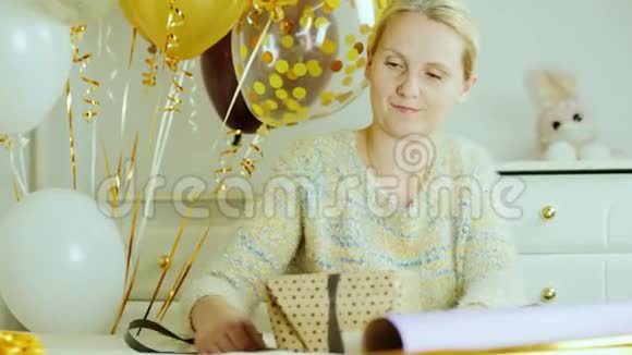一个女人正在为一个孩子准备生日礼物他用一张纸包一个盒子系一条丝带视频的预览图