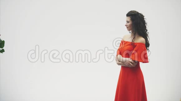 在白色背景下被隔离的美丽浪漫夫妇一个漂亮的年轻女人穿着红玫瑰和裙子视频的预览图