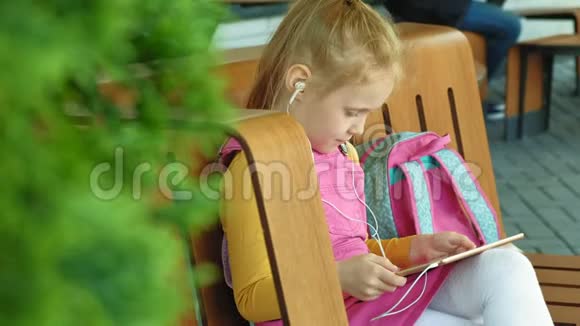 学龄前女孩在户外使用耳机和电脑平板电脑光天化日视频的预览图
