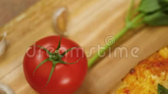 热培罗尼比萨躺在木盘上上面装饰着罗勒绿番茄和大蒜动作缓慢靠近顶部视频的预览图