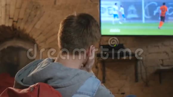 一个年轻人和他的女朋友在电视上看足球视频的预览图