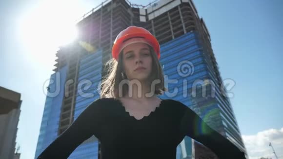 年轻自信的女建筑工人带着褶边站在白天夏天的臀部转过头去建造视频的预览图