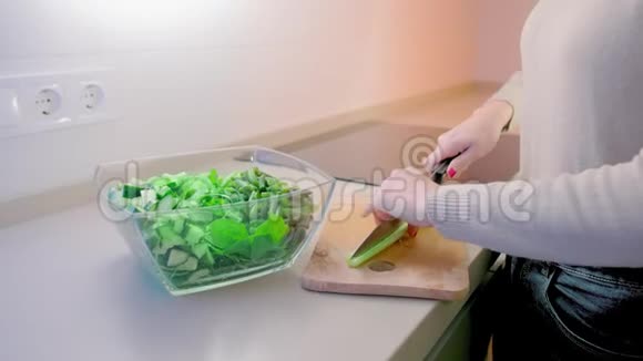 动作缓慢一个未被认出的女人把切好的芹菜倒在木板上放进一个玻璃沙拉碗里里面有一个大厨房视频的预览图