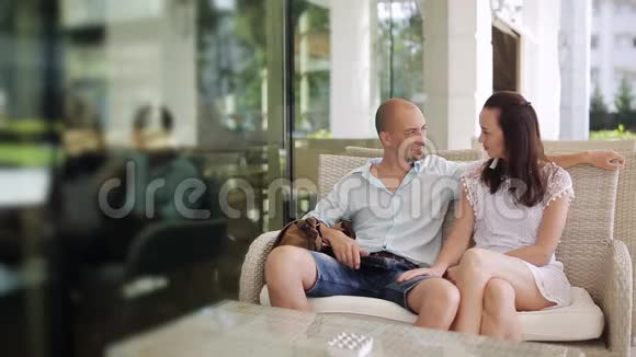 男人和女人在户外咖啡馆的露台上坐在沙发上聊天视频的预览图