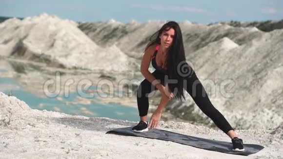 穿着黑色运动服的运动型黑发女孩在一个蓝水白垩沙场上训练从表演卷开始视频的预览图