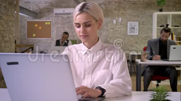 年轻快乐的女商人正在办公室里用笔记本电脑打字同事们正在与技术工作理念建立联系视频的预览图