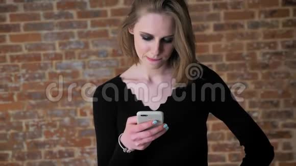 一个眼睛冒烟的年轻女孩正在智能手机上看照片咯咯地笑着交流观念情感观念视频的预览图