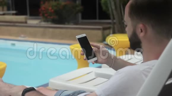 在游泳池里一位男子在一家豪华酒店拿着一部带有互联网的电话视频的预览图