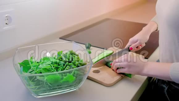 动作缓慢未被识别的女人用一把大菜刀在木板上切黄瓜在前景是视频的预览图