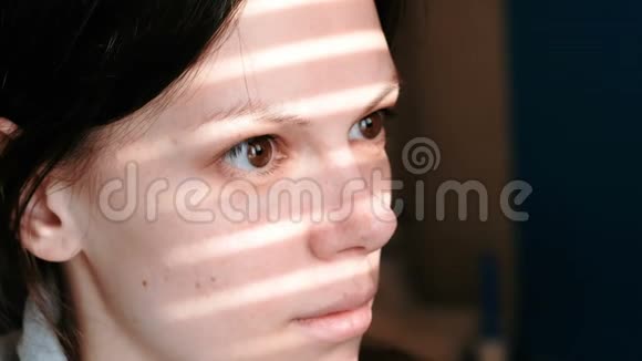 一个黑发女人的特写她的脸上有着窗外的光条视频的预览图
