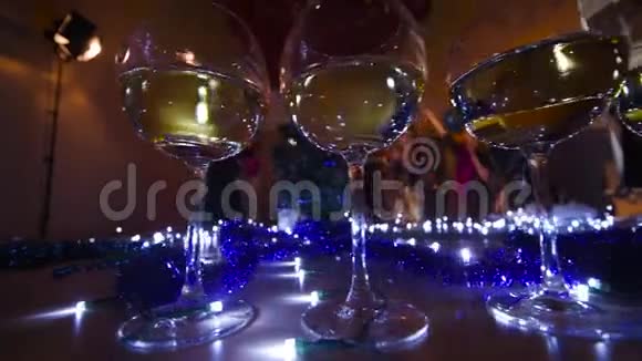 圣诞灯光背景下的香槟酒杯和在圣诞晚会上跳舞的人视频的预览图