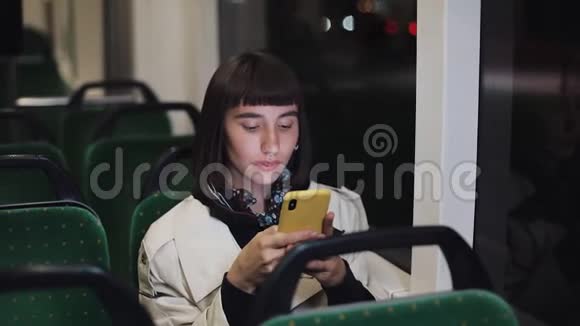 有魅力的年轻女性在公共交通中使用手机她在发短信检查邮件聊天或新闻视频的预览图