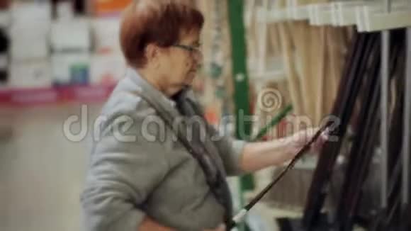 在百货公司的一家超市里一位老年妇女选择了必要的园艺设备视频的预览图