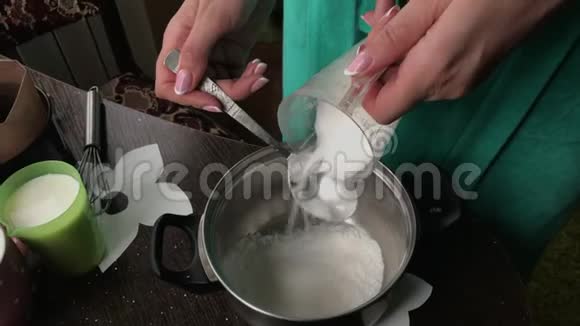 女人在食物中加糖做一个饼干面包屑和牛奶果冻蛋糕桌子表面是配料和烹饪视频的预览图