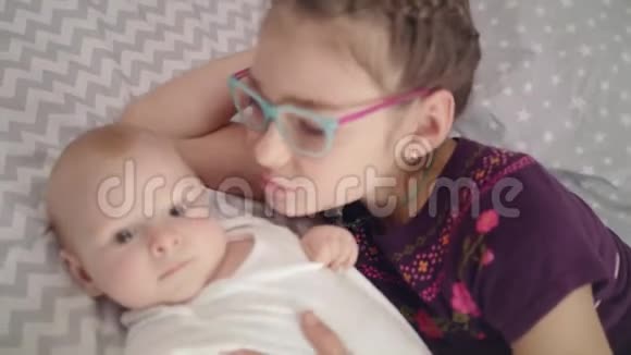 女孩亲吻婴儿姐姐亲刚出生的弟弟姐妹情概念视频的预览图