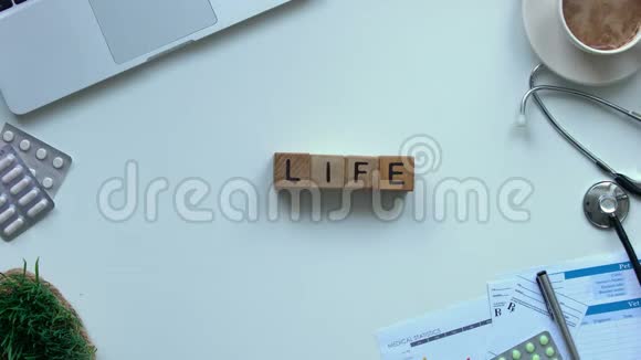 桌子上用木立方体做成的生活字医生用手展示玩具心脏的俯视图视频的预览图