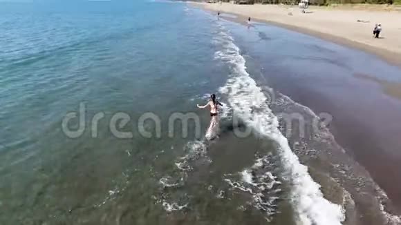 无人机从四面八方移走了一个沿着海滩奔跑的女孩视频的预览图