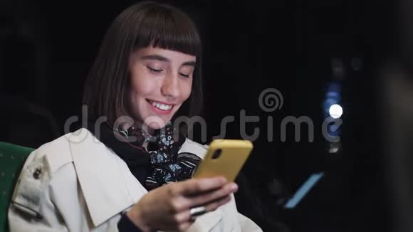 迷人的微笑年轻女子在公共交通工具使用手机她在发短信检查邮件聊天或视频的预览图