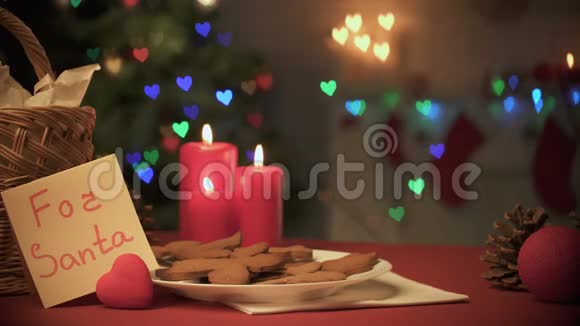 女孩给圣诞老人放了一杯牛奶靠近燃烧的蜡烛和蜂蜜饼干视频的预览图
