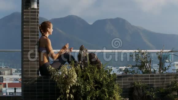 女士戴耳机坐在屋顶露台上视频的预览图