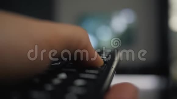 一个手里拿着遥控器的人看电视按下遥控器上的按钮视频的预览图