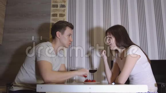 浪漫的夜晚年轻夫妇在餐桌上喝酒吃草莓视频的预览图
