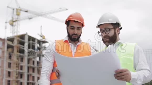 高层建筑施工现场或建筑工地男建筑工程师与建筑师讨论他们视频的预览图