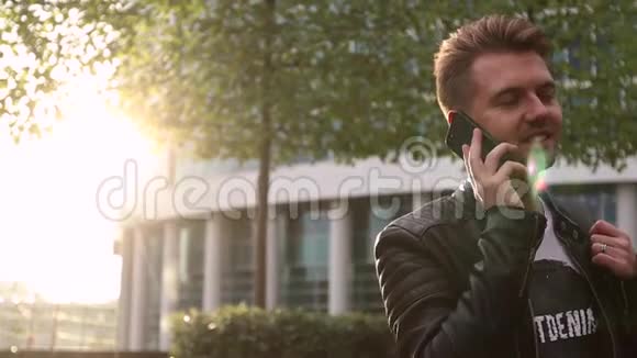 英俊的年轻人站在街上在智能手机上说话视频的预览图
