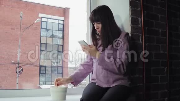 女商人坐在窗台上吃方便面靠在砖楼上视频的预览图