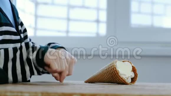 男孩他的手从厨房的桌子上拿着一个喇叭吃冰淇淋穿条纹夹克的面目全非的男孩视频的预览图
