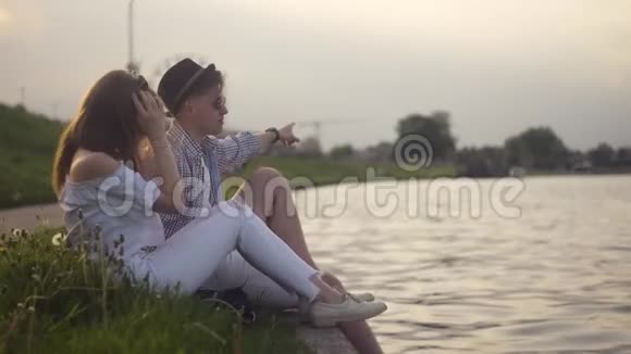 特拉迪夫妇在河边聊天假期假期爱和人的概念快乐的青少年夫妇坐在维斯拉河边视频的预览图