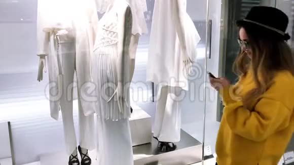 年轻的黑发女孩在网上购物女孩在商店里挑选衣服并通过网上电话购买穿黄色毛衣的女孩视频的预览图