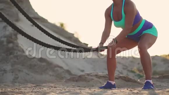 一个带绳子的女孩的特写在海滩附近的沙地上进行户外训练女人手中的绳索视频的预览图