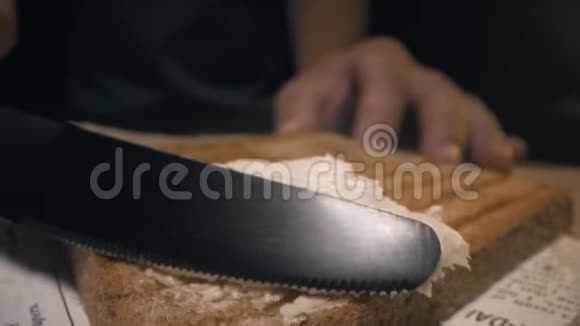 特写镜头厨师用刀把黄油涂在脆烤面包上做三明治自制快餐视频的预览图