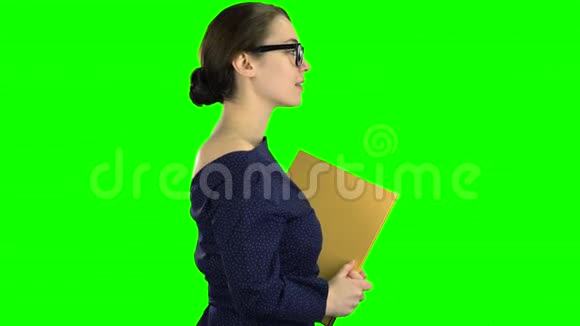 女孩走在街上手里拿着一个黄色的文件夹绿色屏幕侧视图视频的预览图