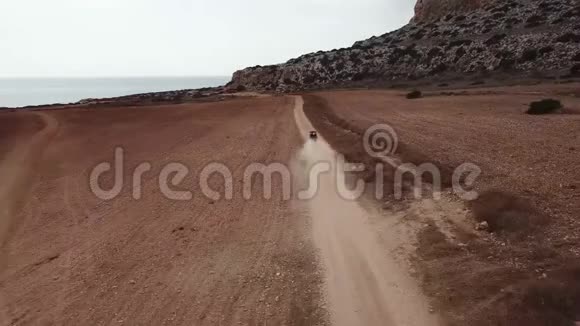 电影镜头汽车穿越红色沙漠土地在空中投掷沙子和泥土被海洋包围视频的预览图