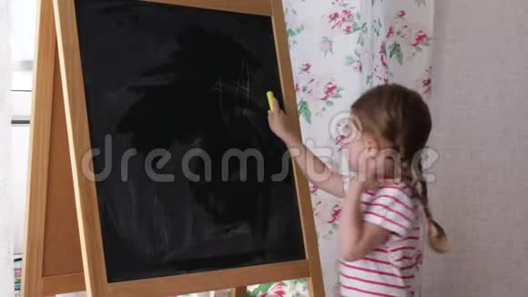 学龄前小女孩在黑板上写字母幼儿女孩拿着粉笔画画视频的预览图