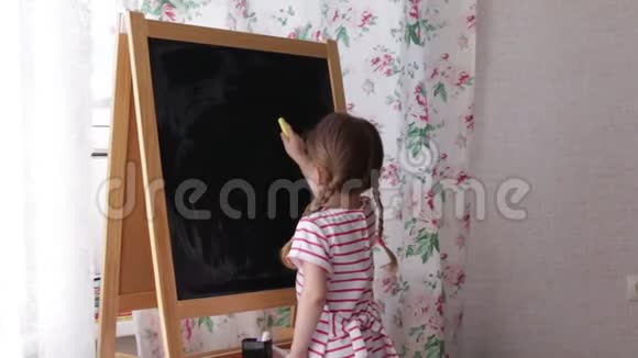 学龄前小女孩在黑板上写字母幼儿女孩拿着粉笔画画视频的预览图