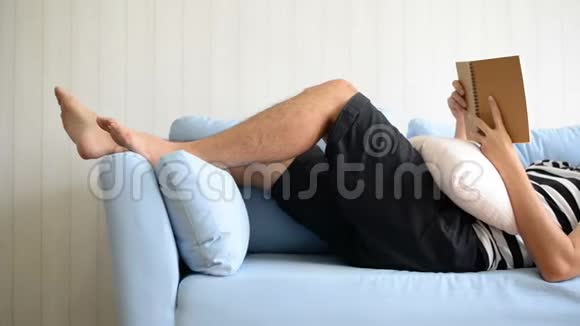 亚洲男人躺在沙发上在家看书视频的预览图