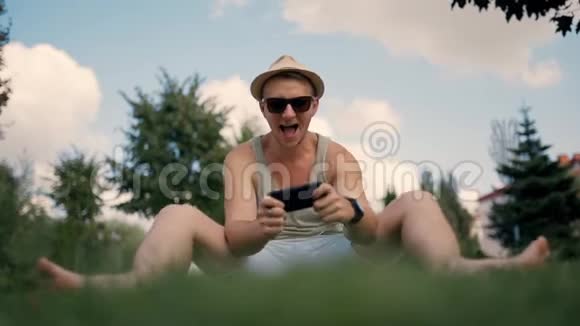 在公园玩智能手机的快乐男人视频的预览图